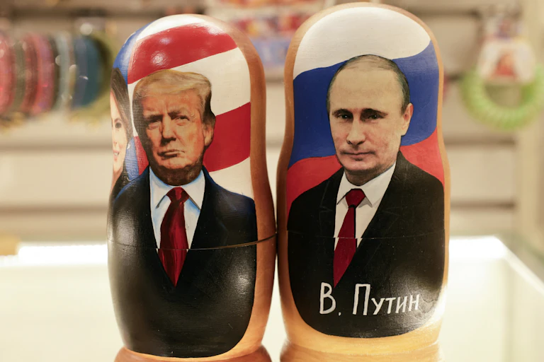 Two wooden dolls show two men wearing dark suits and red ties.