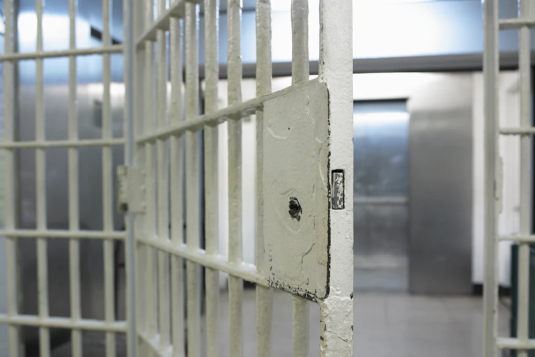 An open door to an empty prison cell.