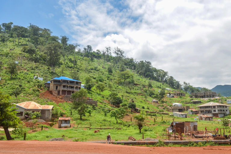 green hill with a few huts and houses, blue sky