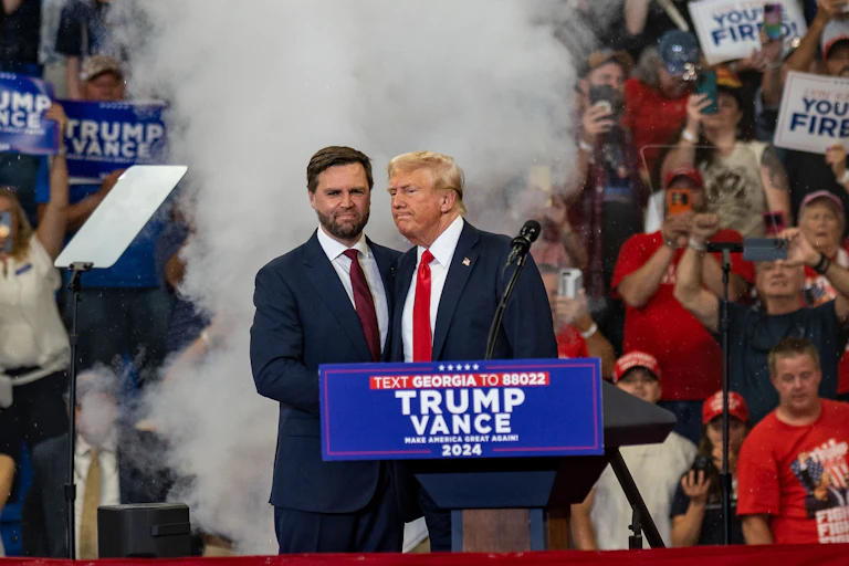 US Vice President JD Vance shakes hands with Donald Trump at a rally.