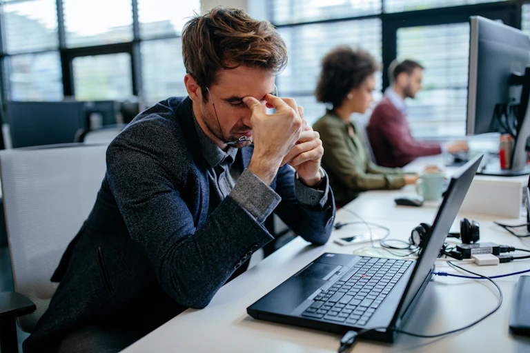 Unhappy worker in an office looking at his laptop