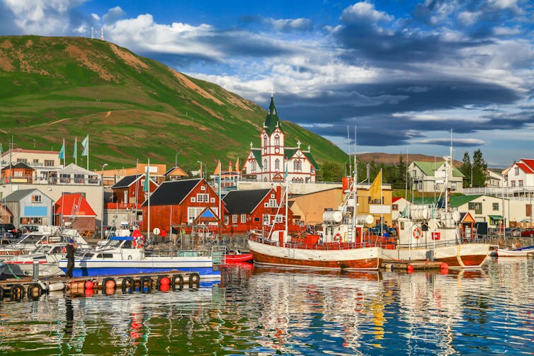 View of the historic town of Husavik with traditional colourful houses and traditional fisherman boats in Iceland.