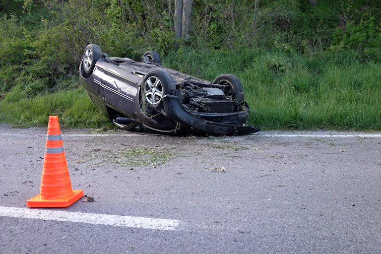 Overturned, crumpled car on the side of the road.