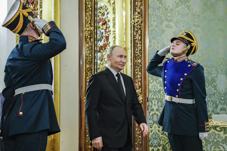 Two men in soldier uniforms salut man in suit walking entering a room.