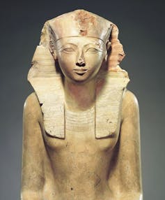 A sandstone statue of Hatshepsut in a pharoah's headdress.