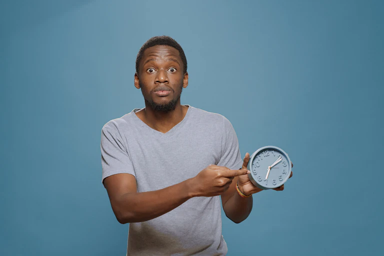 Man points to clock with stressed expression.