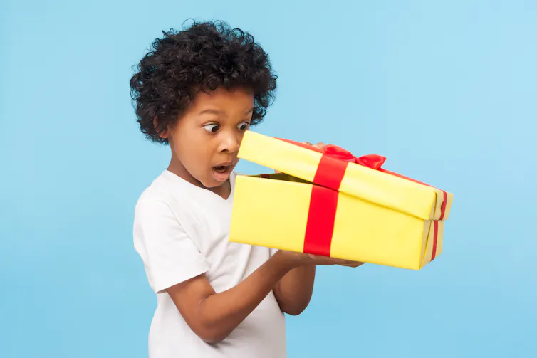 Young boy peeks inside wrapped box.