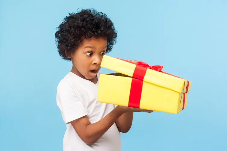 Young boy peeks inside wrapped box.