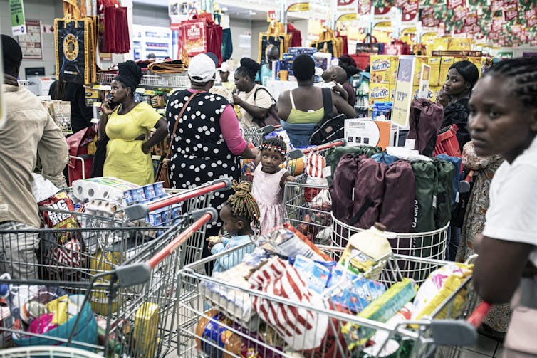 Women with trolleys filled with groceries at a supermarket.