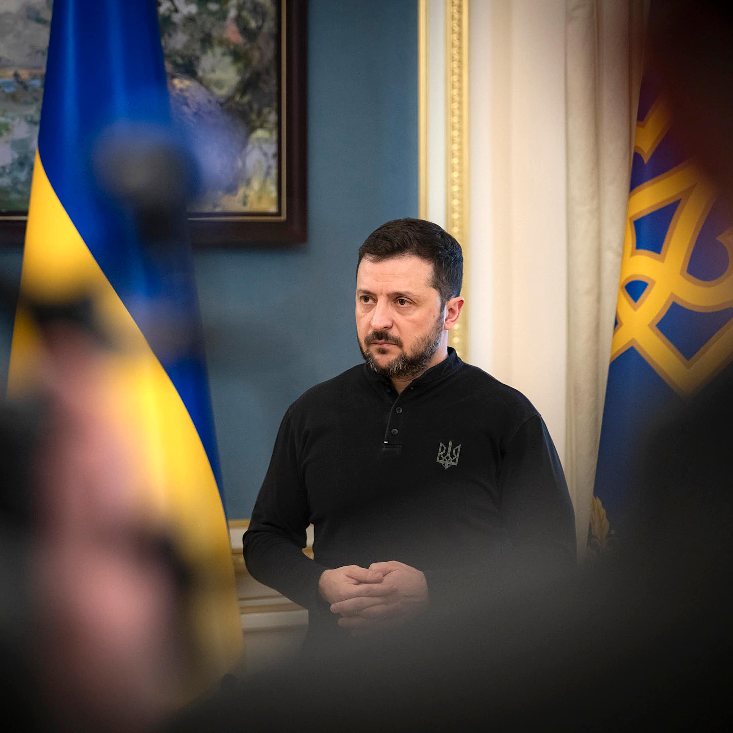 Ukraine's president Volodymyr Zelensky, flanked by his country's flags.