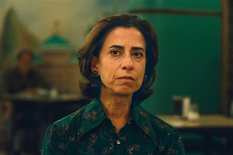 A woman looking serious against the dark green background of her home.