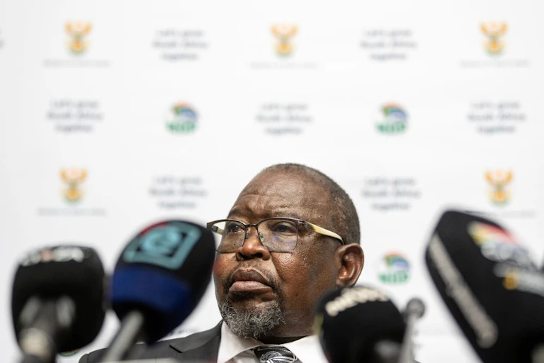 Head of man wearing spectacles with microphones in the foreground