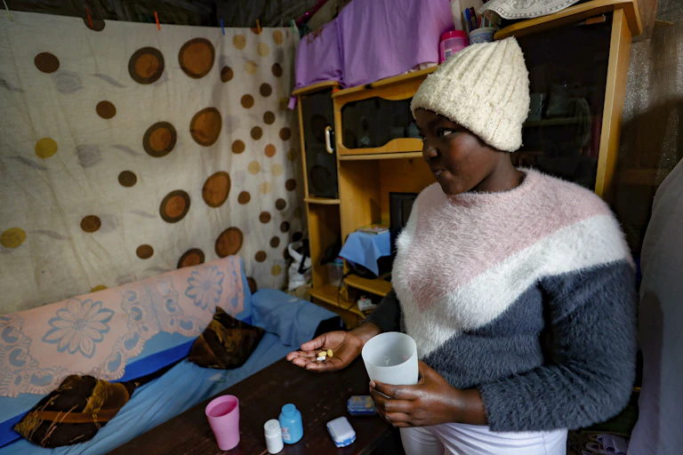 A young Kenya woman takes anti-retrovirals pills.