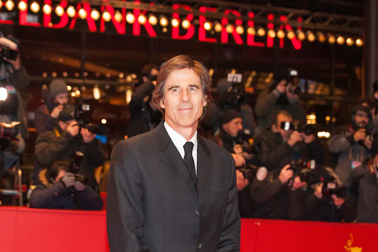 A middle-aged man in a suit standing on the red carpet at the Berlin film festival.