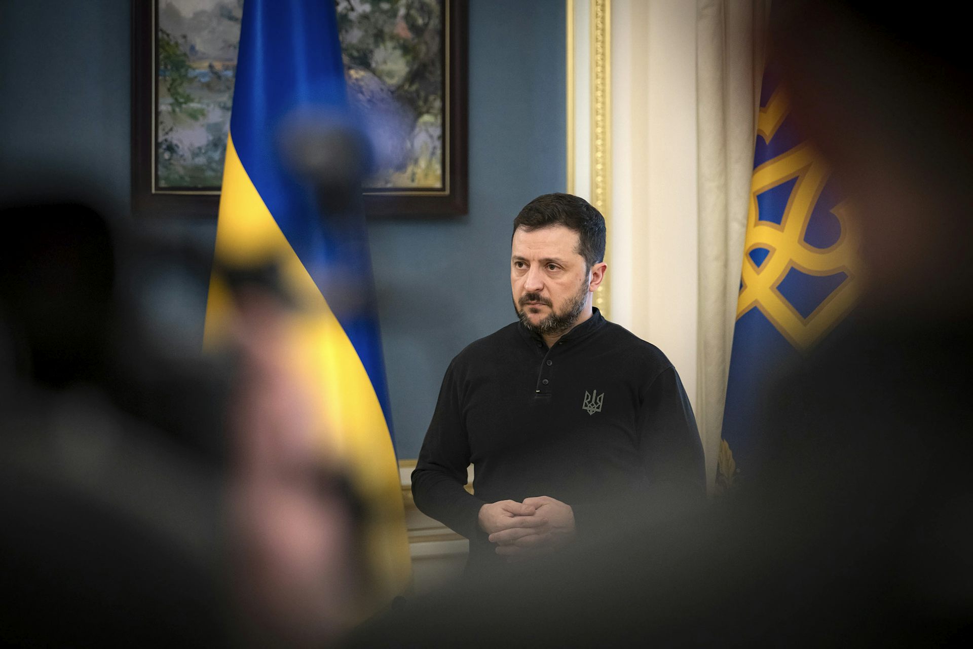 Ukraine’s president Volodymyr Zelensky flanked by two national flags.