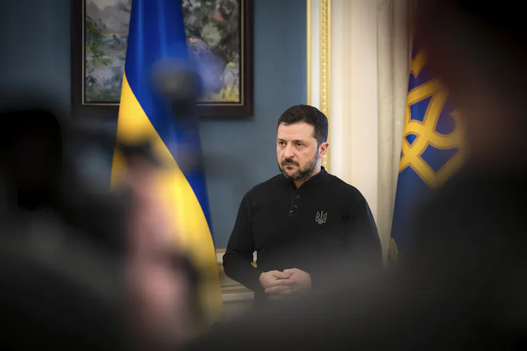 Ukraine’s president Volodymyr Zelensky flanked by two national flags.
