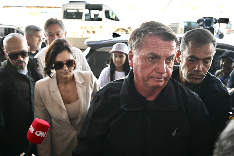 A man in a black jacket stands with men and women either side.