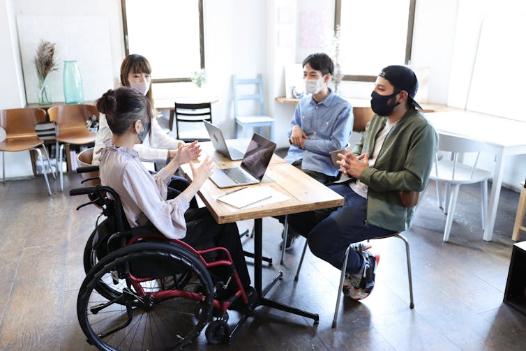 Woman on wheelchair with her colleague at office