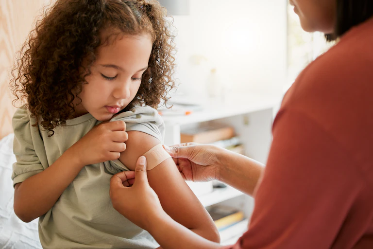 Nurse puts bandaid on girl's arm after a vaccination