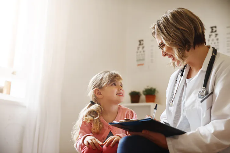 A girl and clinician smile at each other