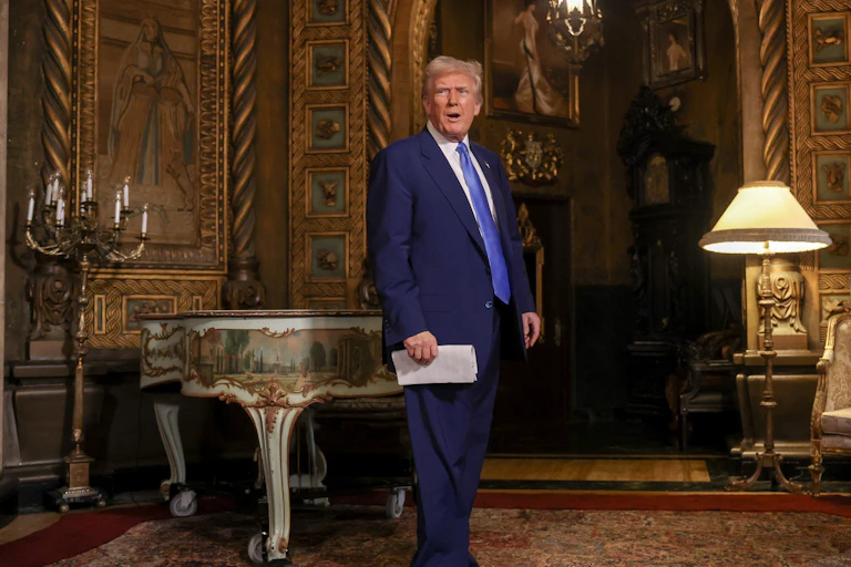 Donald Trump stands in a golden-furnished room