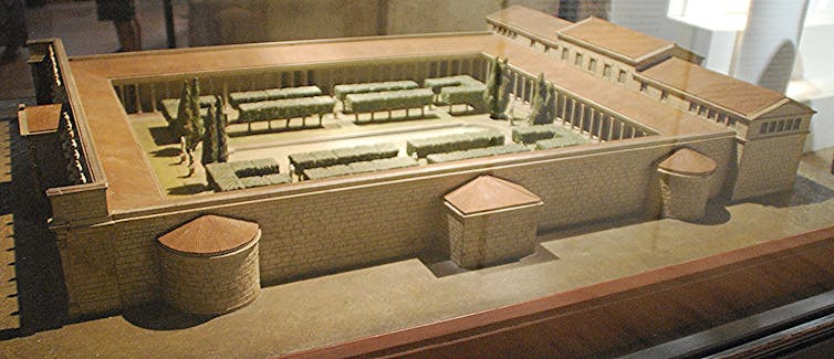 A diorama seen from above, showing a large building with an open courtyard and sloped roof.
