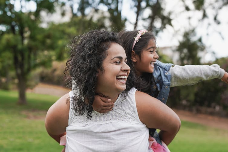 A woman in her forties gives her daughter a piggyback ride.