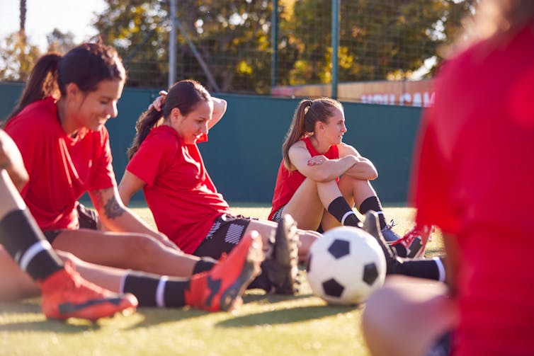 A women's soccer team sitting on the ground resting.