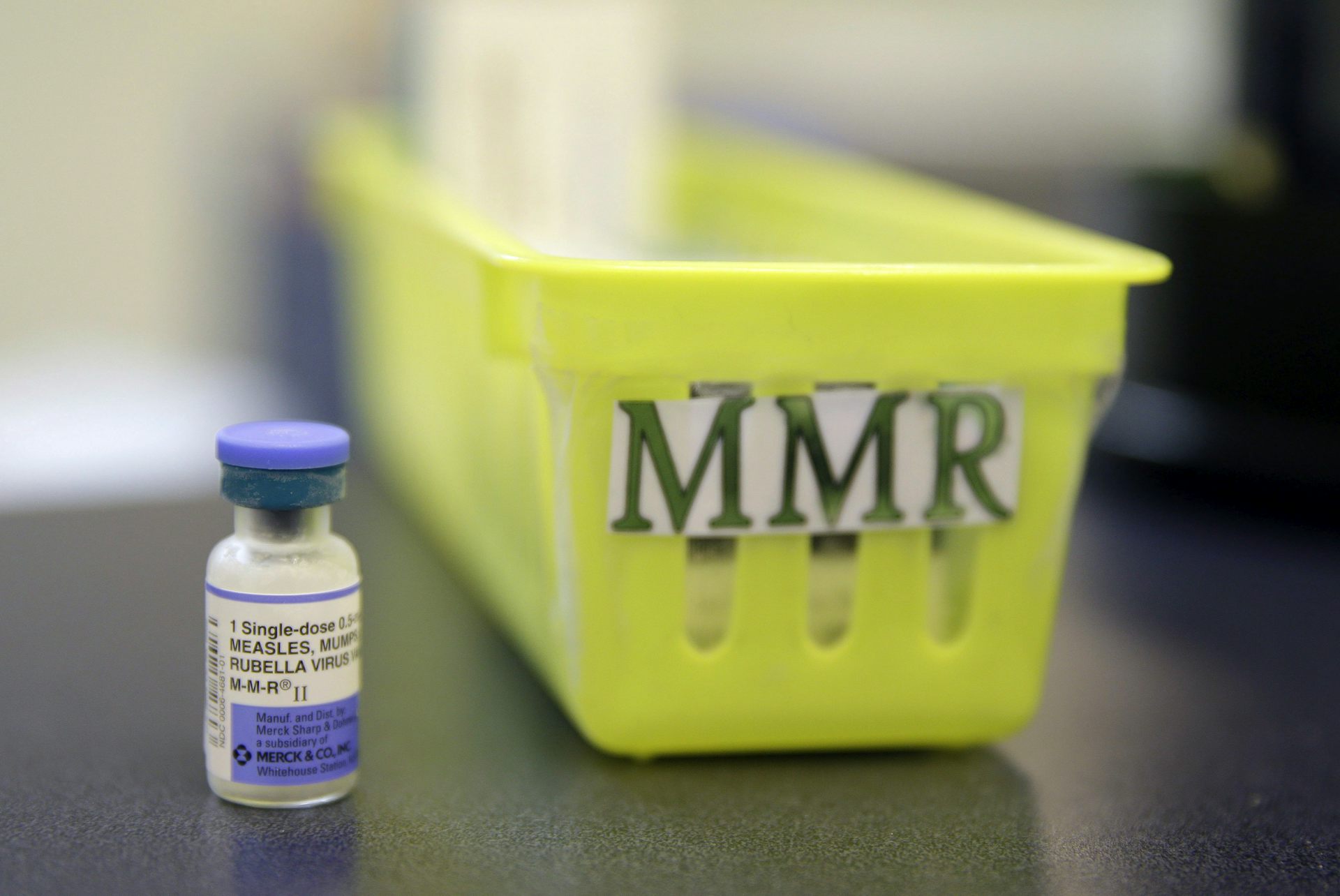A yellow plastic tray labelled MMR with a vial of vaccine beside it