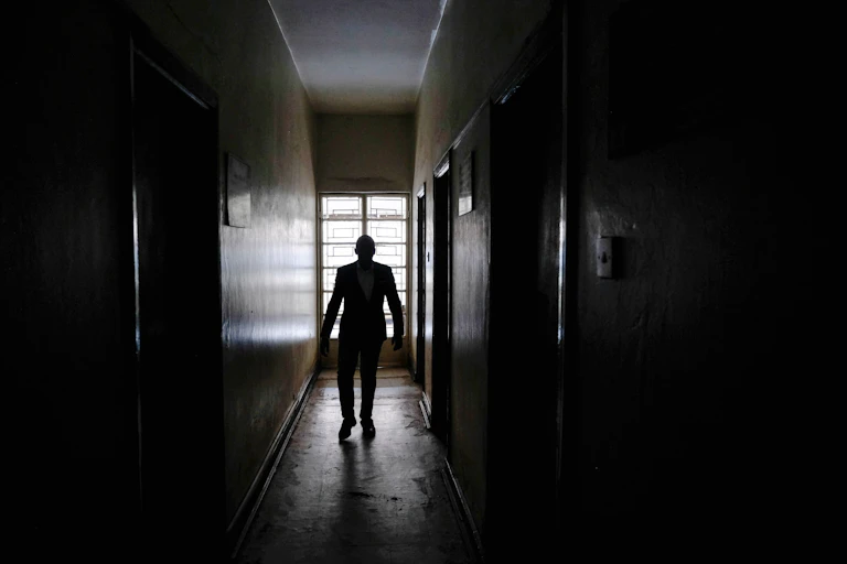 Silhouette of man walking down dark, empty corridor