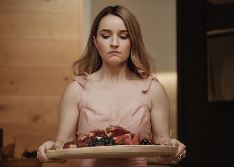 An explosion of color and the downfall of an Instagram darling – what to look and watch this week 3 A young woman looking down at a tray of fruit.