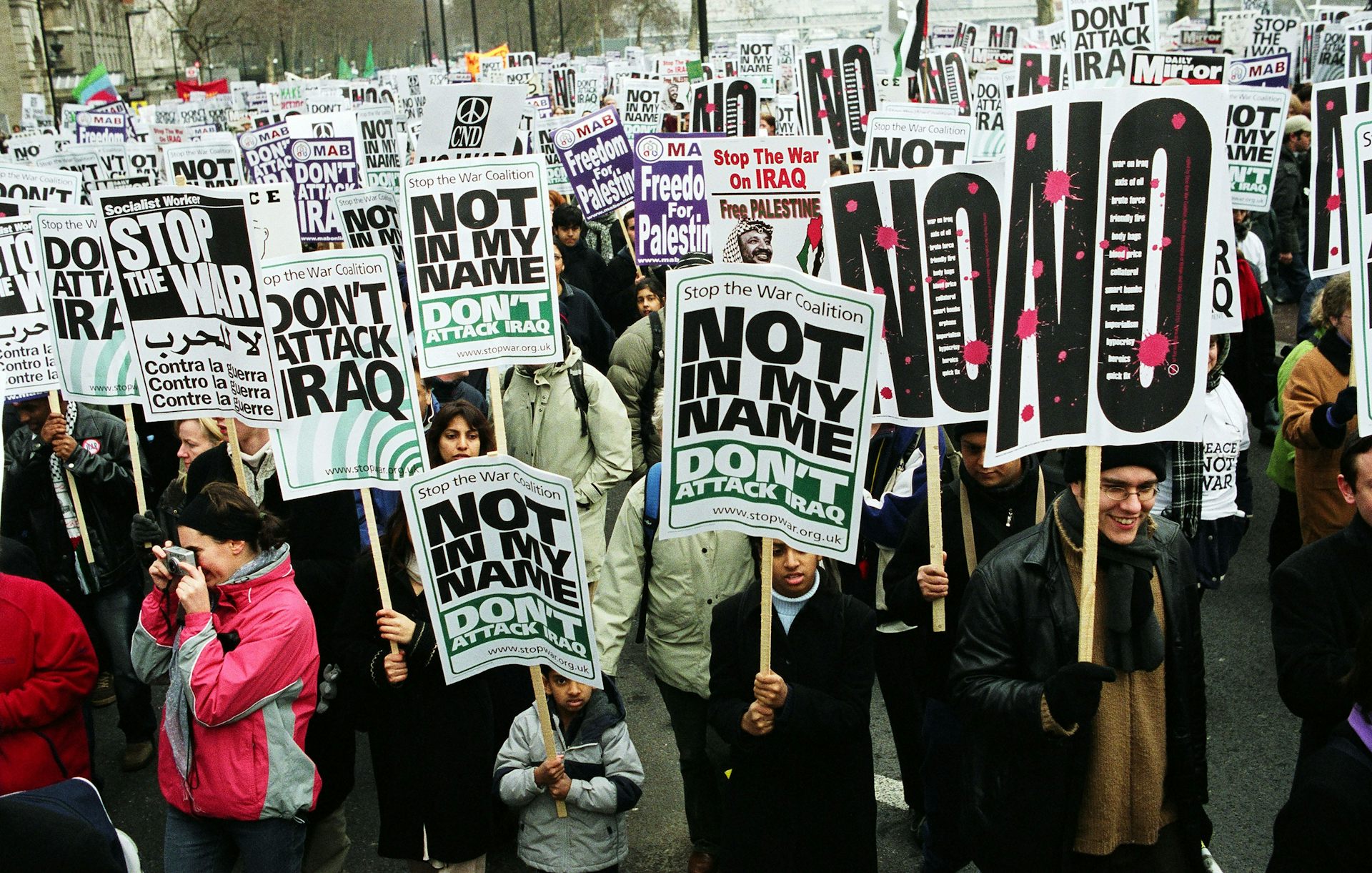 A large crowd of people carrying signs against invading Iraq