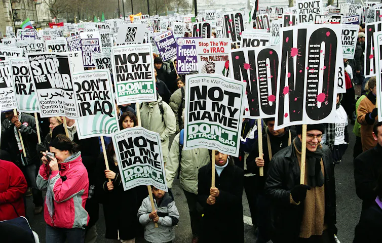 A large crowd of people carrying signs against invading Iraq
