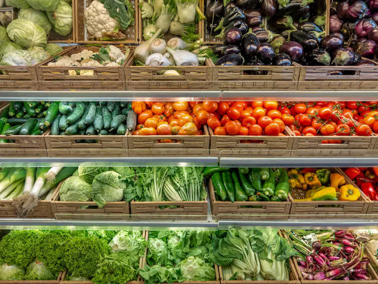 Crates of fruit and vegetables in a shop aisle.