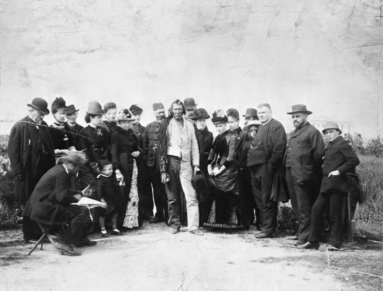 Group of men standing in a line focused on one man in the centre.