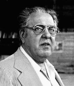 Albert 'Cubby' Broccoli in a suit with glasses, black and white photo.