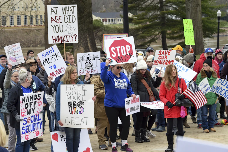 People at a demonstration carry placards and homemade signs