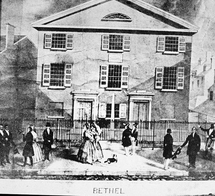 Black and white drawing of three-story building and people mingling on sidewalk in front