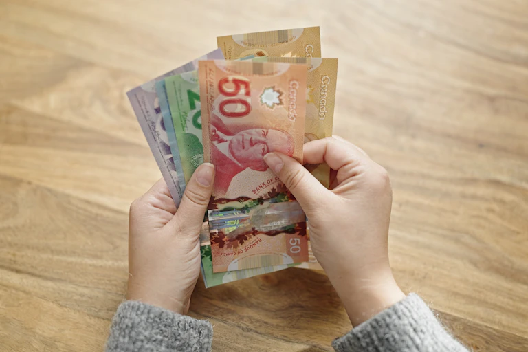 Close up of a person's hands counting notes of Canadian currency