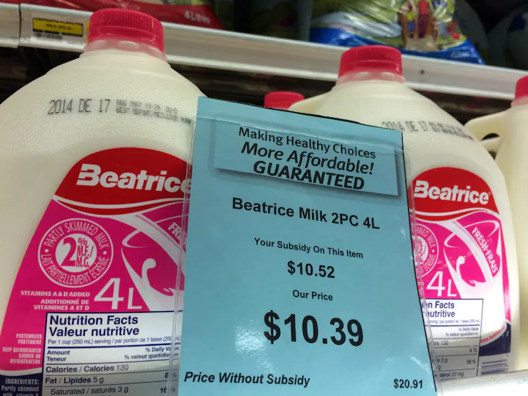 jugs of milk on a store shelf with a subsidy price of $10.39 and regular price of $20.91