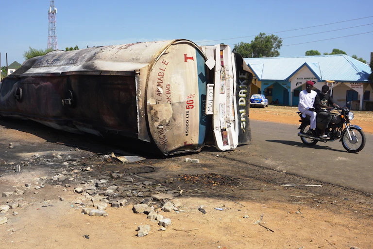 Fuel tanker lying on its side; motorcycle passes