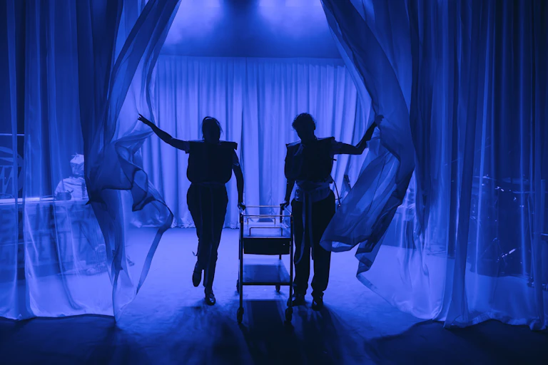 A silhouette of two women on a blue stage.