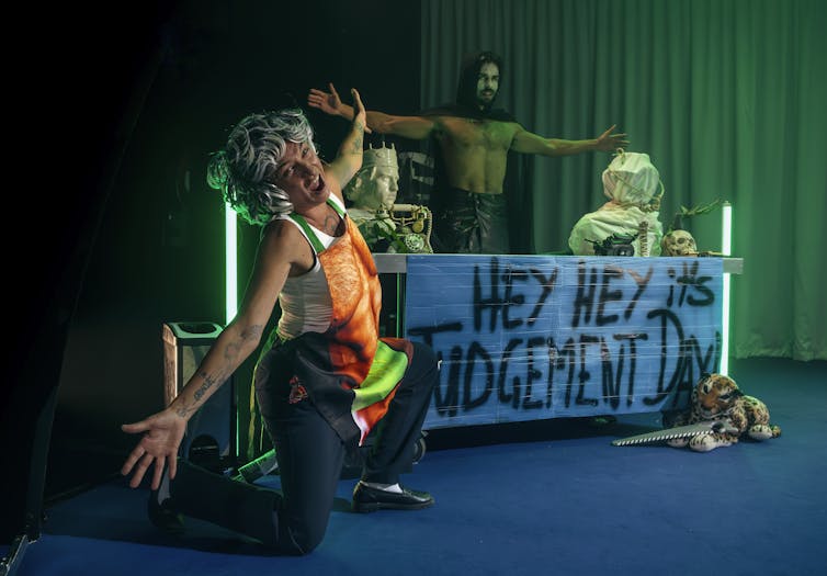 A sign reads Hey Hey It's Judgment Day, two actors appear to be saying ta-da.