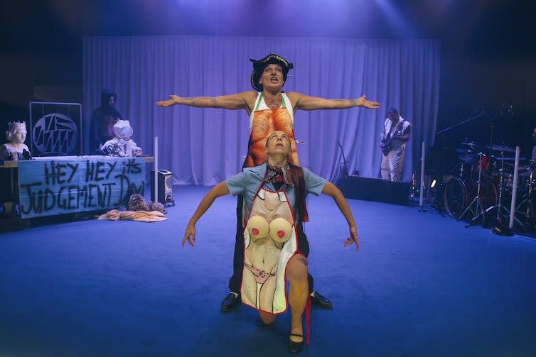 Two women pose in aprons depicting scantily dressed torsos.