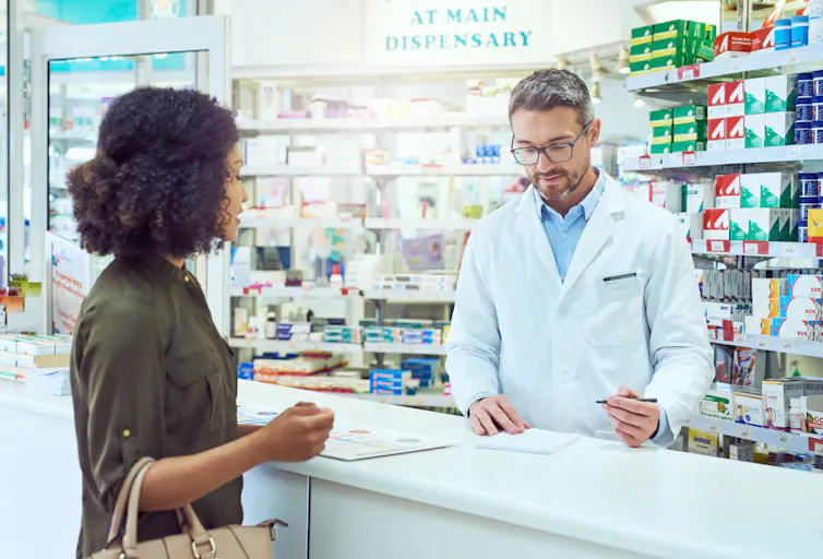Pharmacist talks to a woman at the counter.
