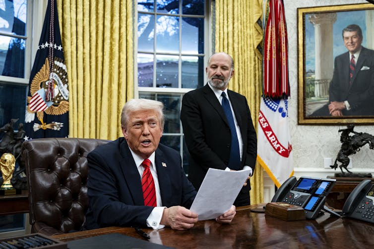 Man sitting at desk holding papers
