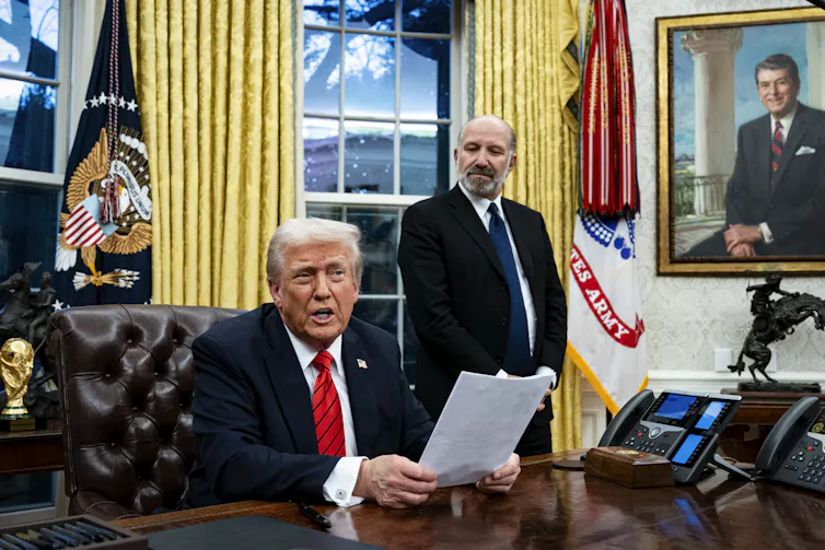 Man sitting at desk holding papers