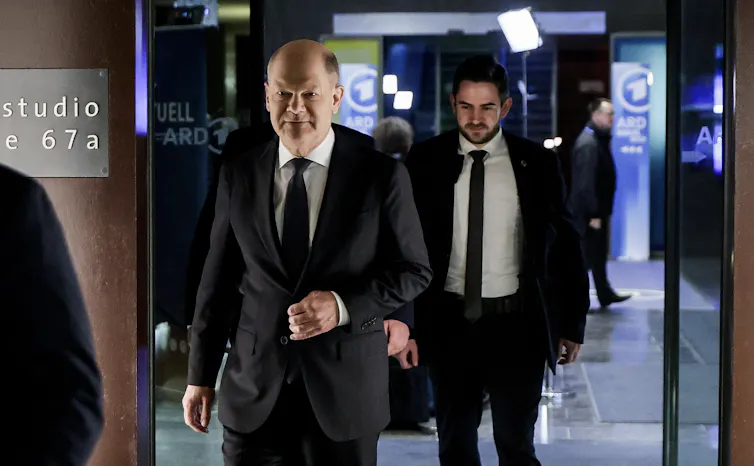 Olaf Scholz in suit leaves a building at night.
