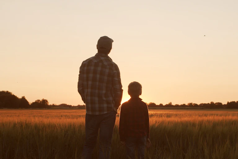 farmer and his son looking at sunset