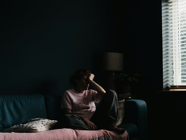 woman sitting on couch with head in hand